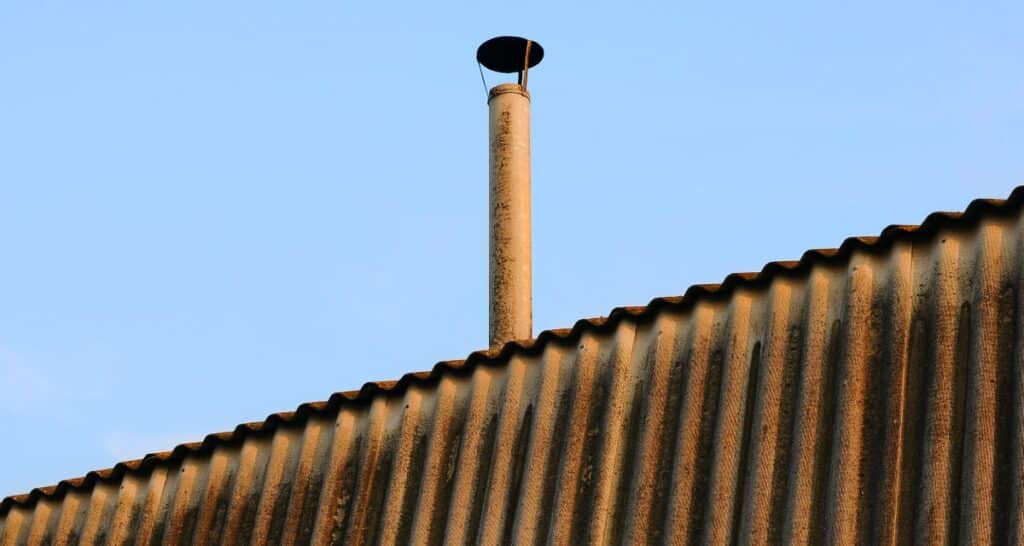 dak met asbesthoudende schoorsteen en asbestgolfplaten