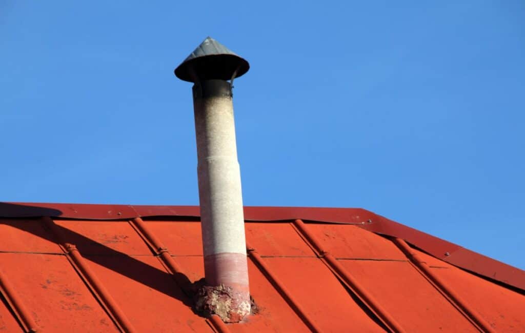schoorsteen met asbest op dak met rode dakpannen