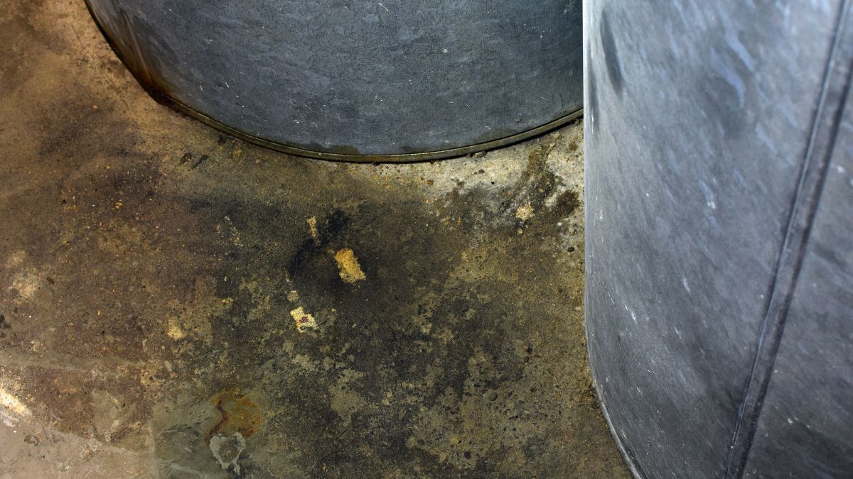 Detail van twee mazouttanks met lekkages. Op de grond onder de tanks zitten donkere vlekken.