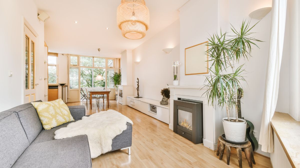 Lichte woonkamer met witte crepimuren, hoog plafond, moderne gashaard en veel natuurlijk licht door grote ramen