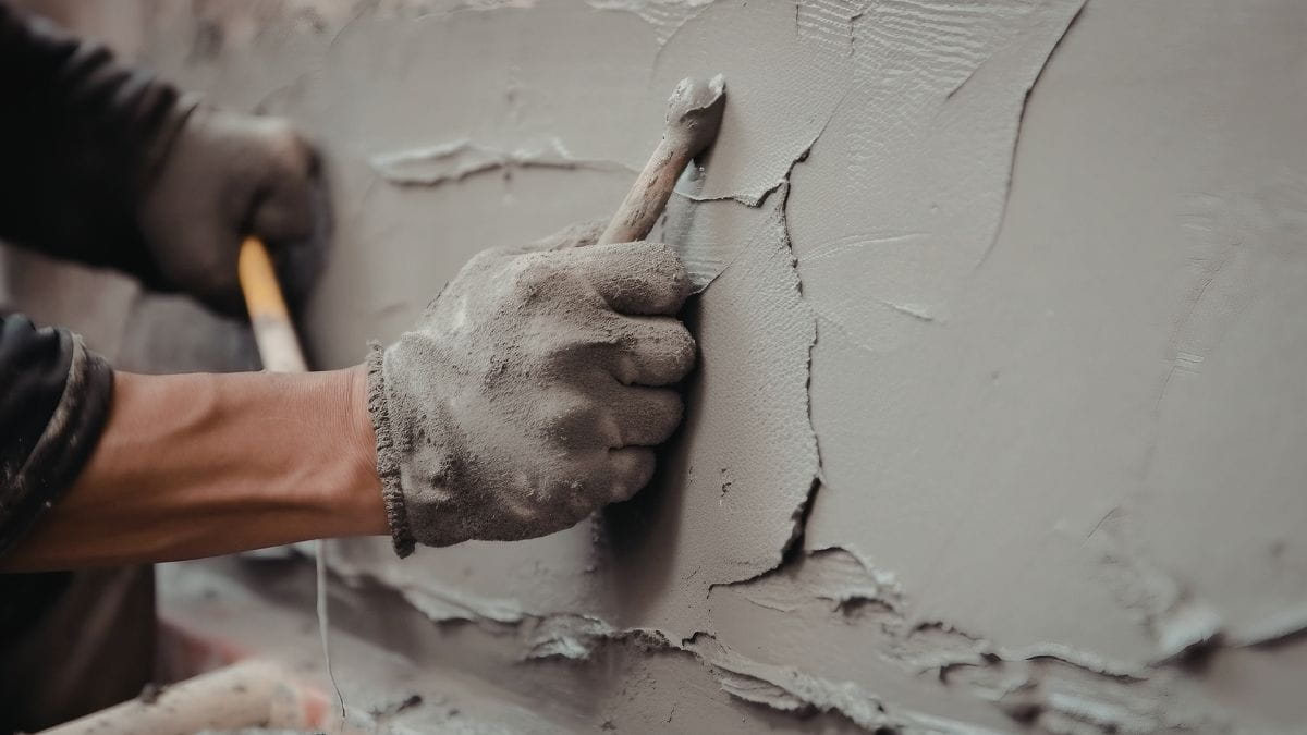 Stukadoor brengt sierpleister binnen aan met de correcte materialen en handschoenen