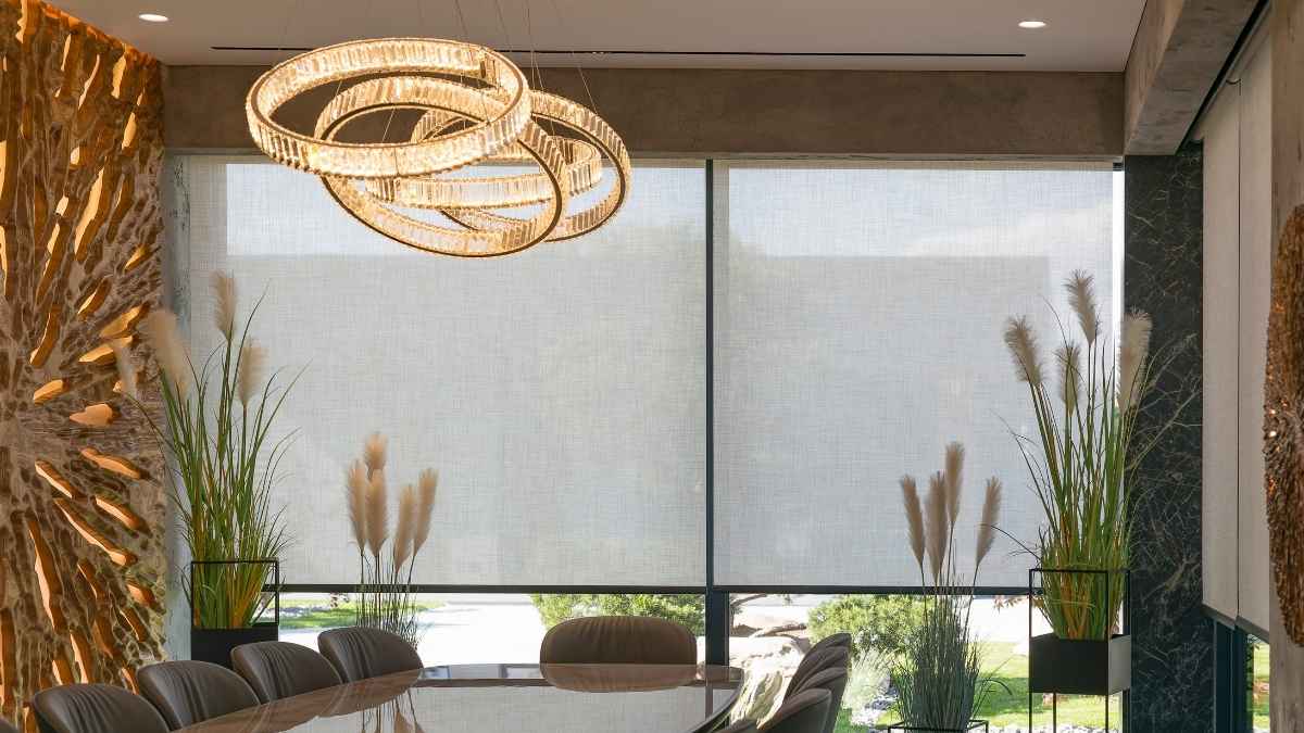 Een eetkamer met glanzende tafel en designstoelen. Achteraan zit een groot, breed raam. Voor het raam hangen semi-transparante screens als zonwering.