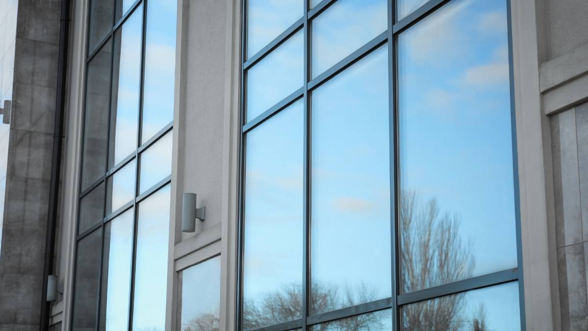 Een bijna volledig glazen gevel, met grote zonwerende ramen. Het zonwerend glas is voorzien van een reflecterende coating die zonnestralen weerkaatst en infraroodstraling filter. De ramen reflecteren de blauwe hemel en enkele kale bomen.