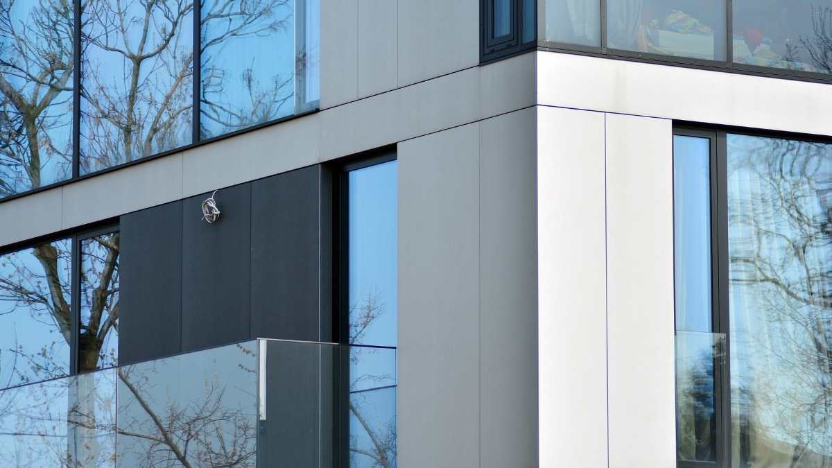 Een moderne grijze gevel met grote ramen met reflecterend 4-seizoensglas of zonwerend glas. 
